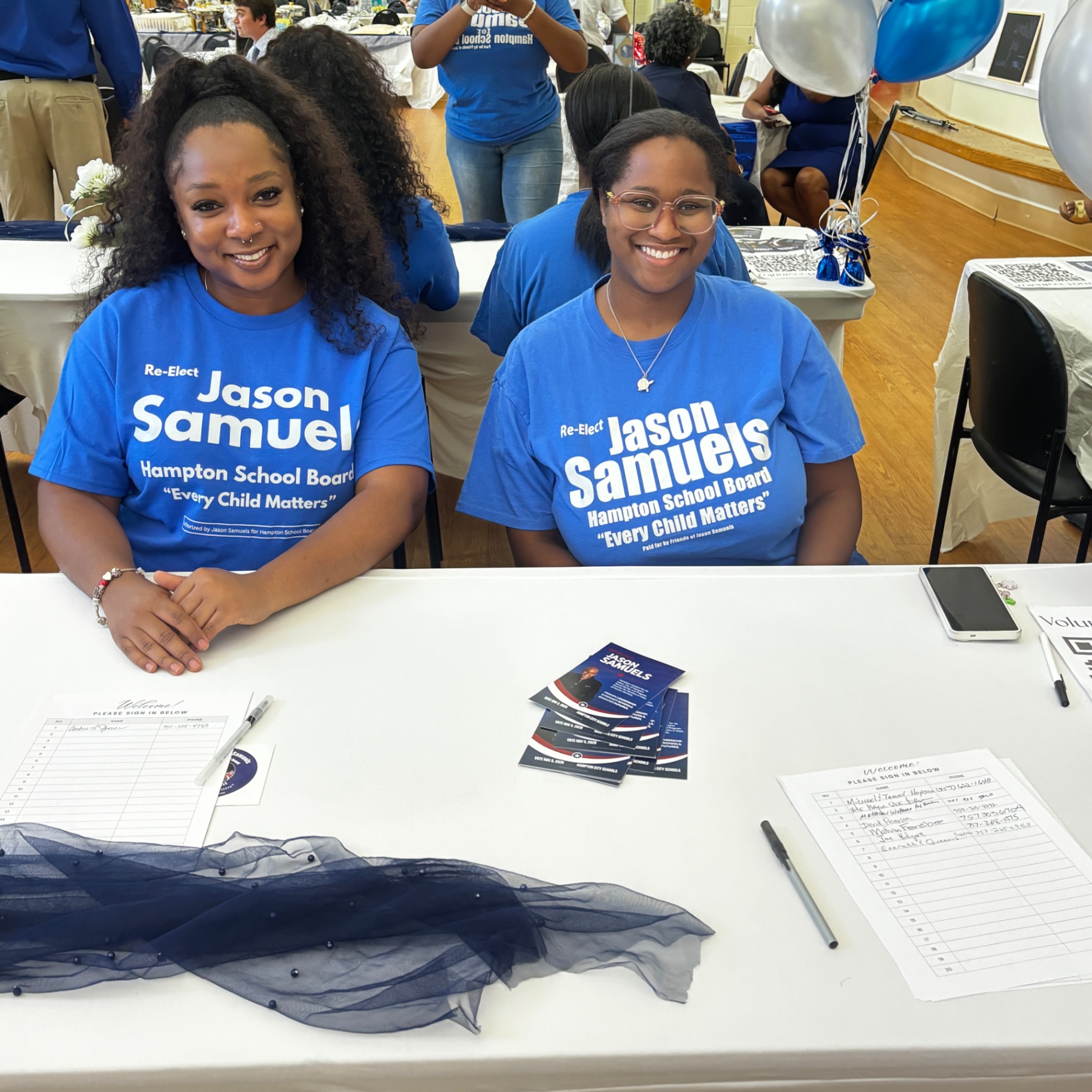 Two volunteers in blue Jason Samuels campaign shirts seated at the welcome and sign-in table during the August 23 kickoff school supply drive.